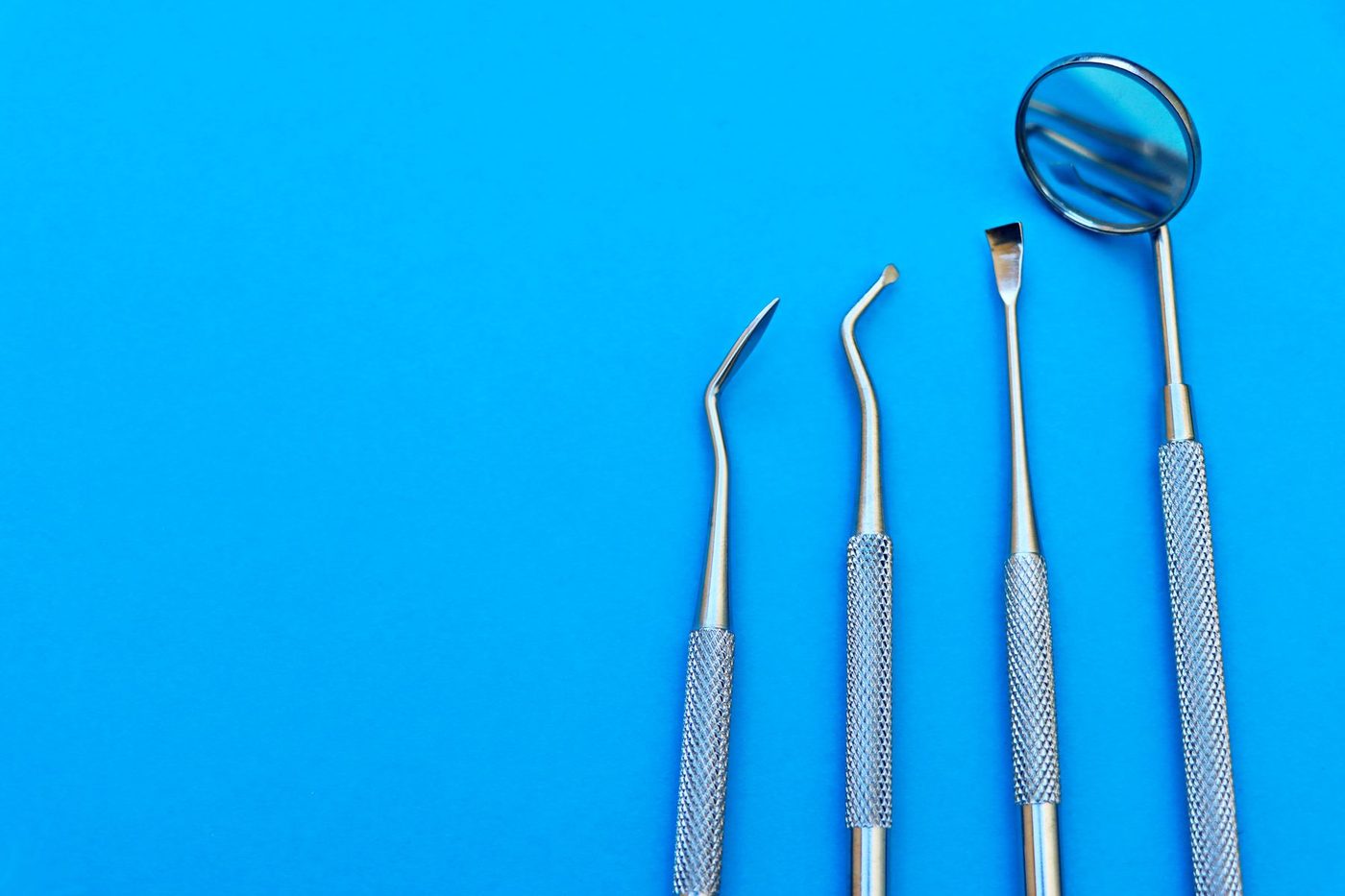 A dental mirror and hand instruments on a blue background